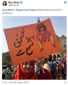 Pakistani woman at protest holding sign of woman sitting spread-legged